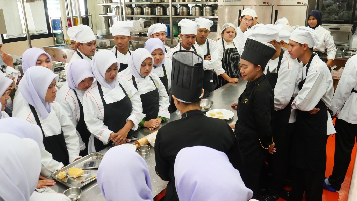 A group of chefs in a kitchen

Description automatically generated