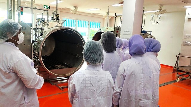 A group of people in white coats and white coats in a room

Description automatically generated