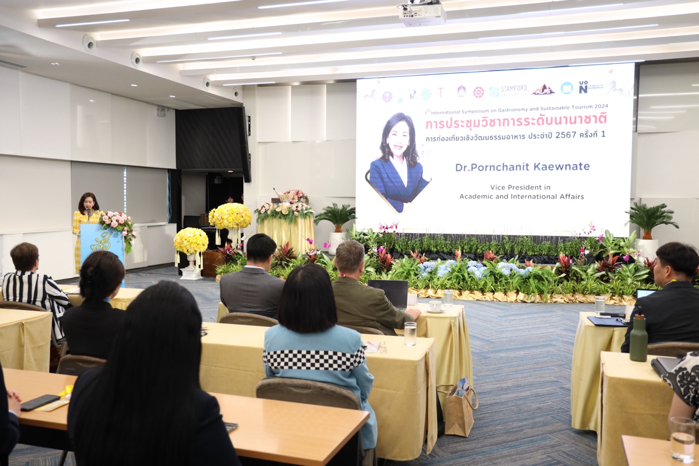 A group of people sitting at tables in front of a projection screen
Description automatically generated