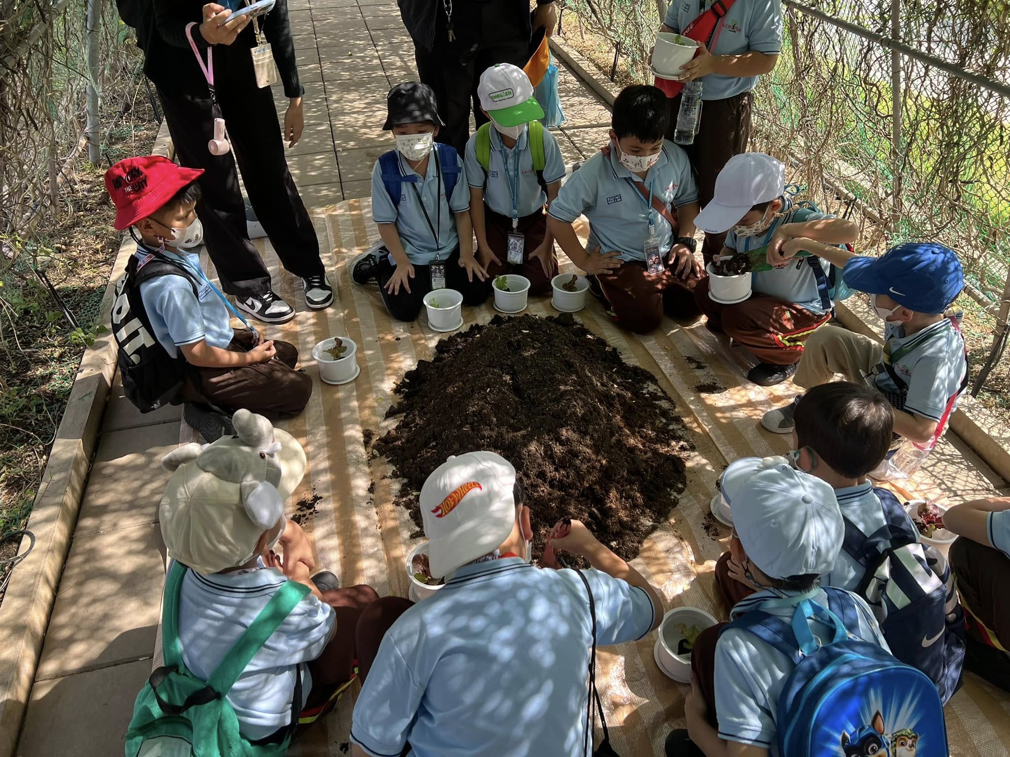 A group of people sitting on a table with a pile of dirt

Description automatically generated