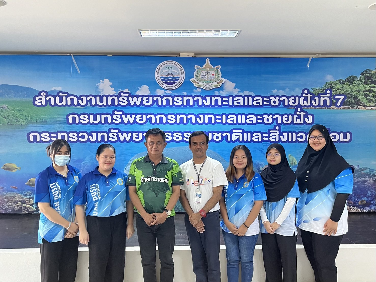 A group of people standing in front of a banner

Description automatically generated