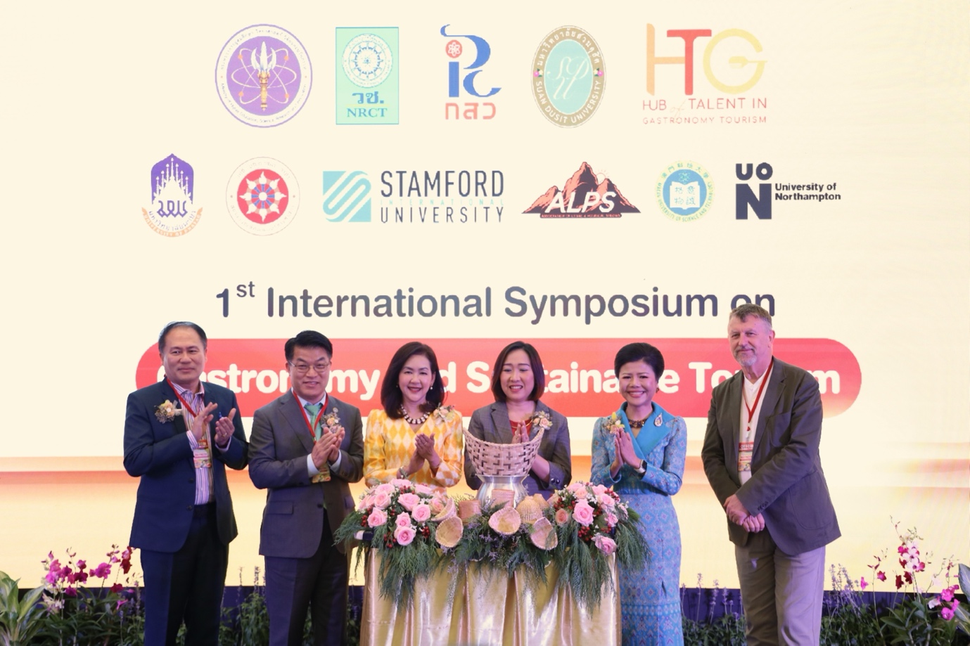 A group of people standing in front of a large banner

Description automatically generated