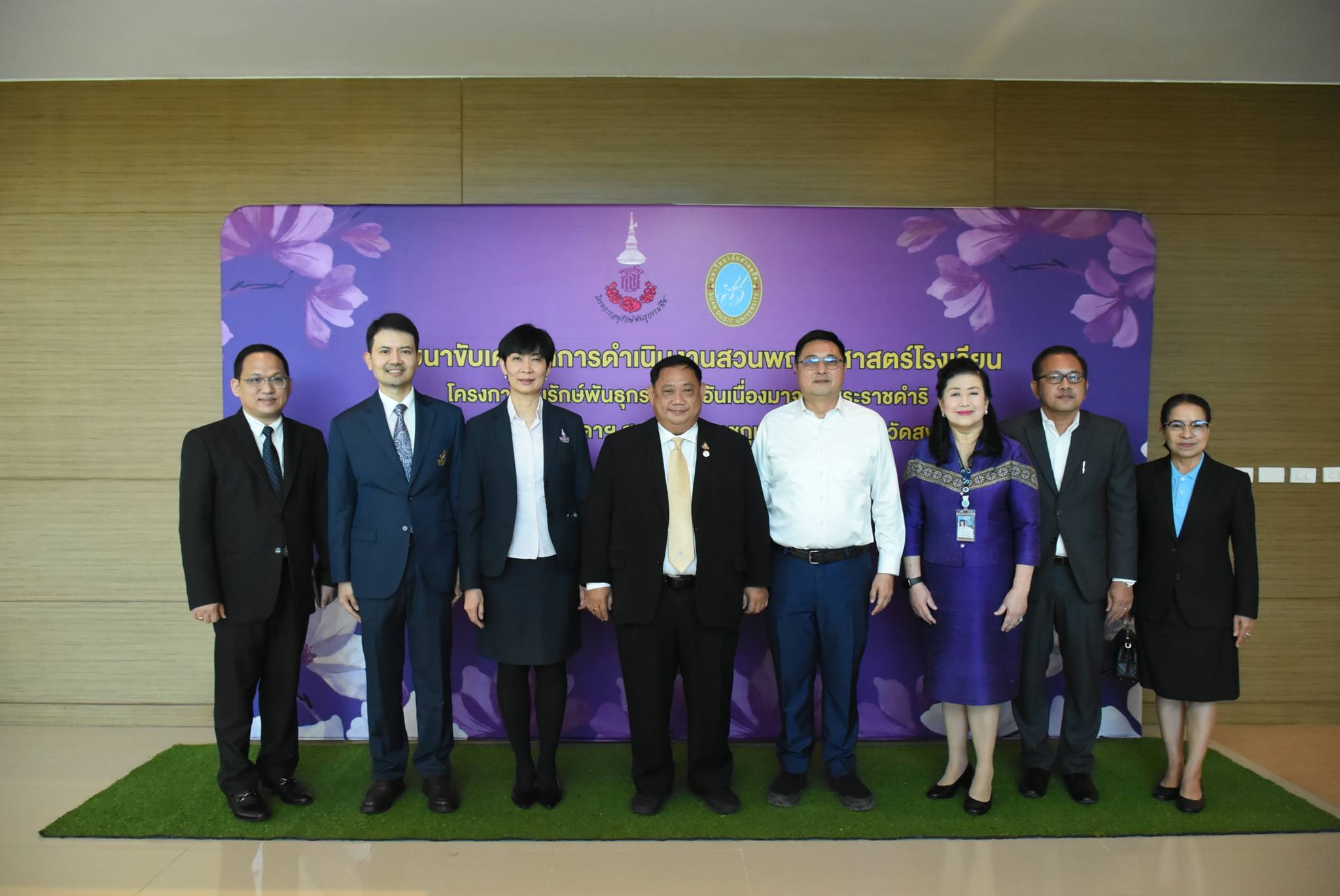A group of people standing in front of a purple banner

Description automatically generated