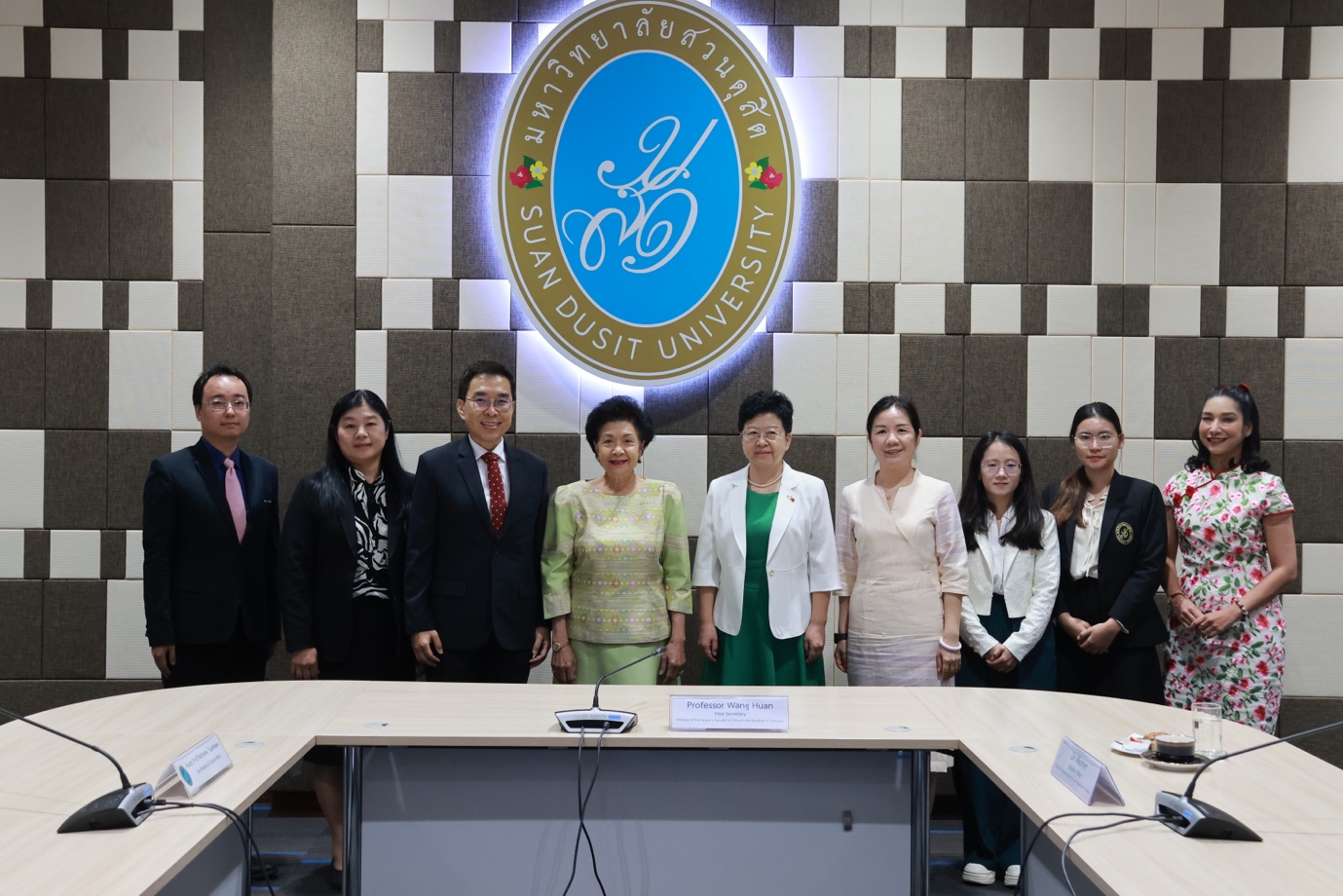 A group of people standing in front of a sign

Description automatically generated