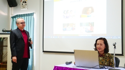 A person and person standing in front of a computer
Description automatically generated