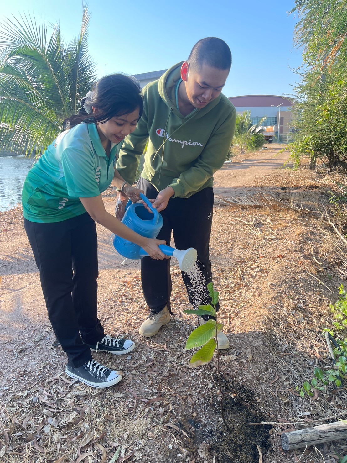 A person and person watering a plant

Description automatically generated