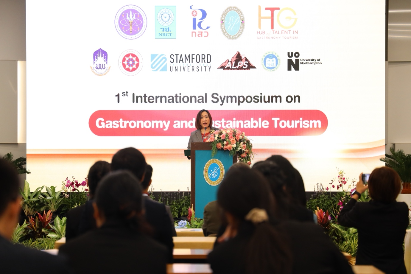 A person giving a speech at a conference

Description automatically generated