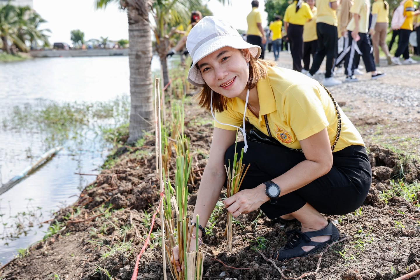 A person kneeling in the dirt next to a body of water

Description automatically generated
