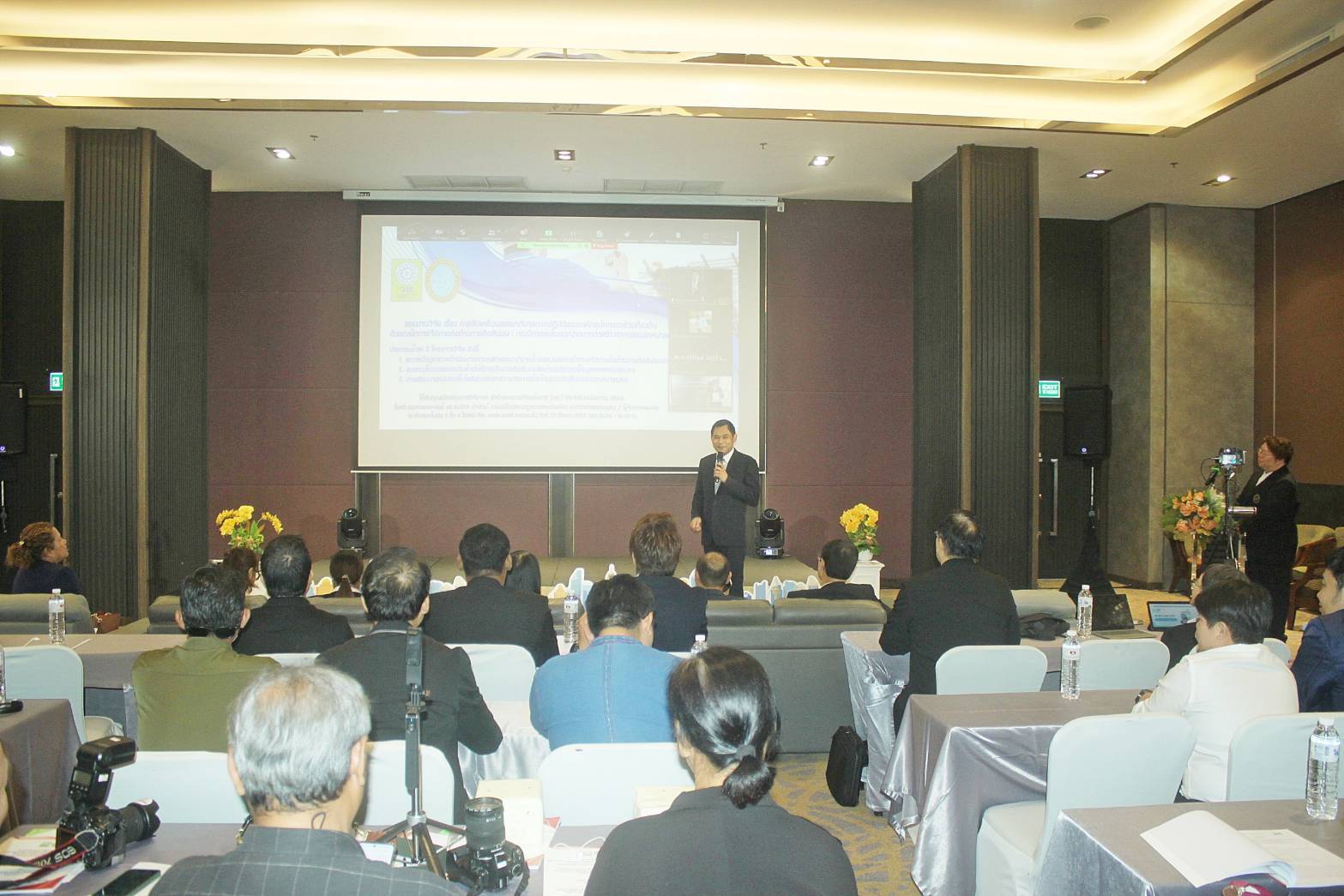 A person standing in front of a large screen
Description automatically generated