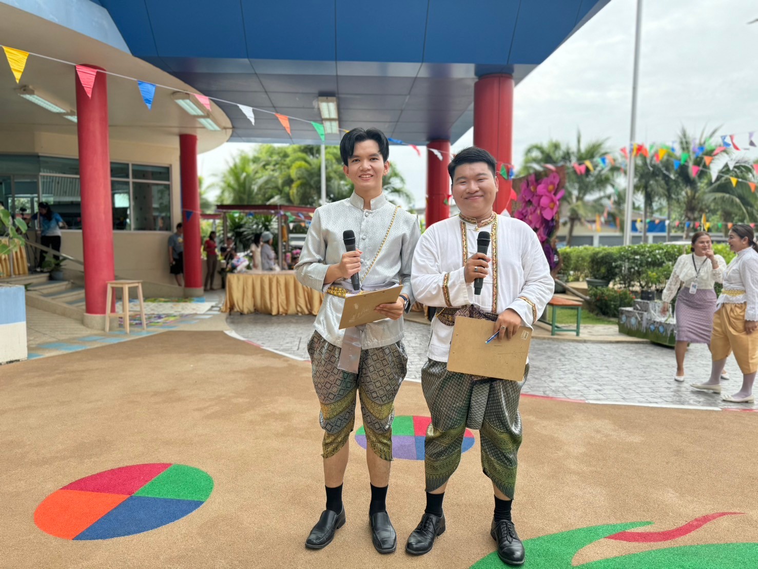 Two men holding microphones and holding papers
Description automatically generated